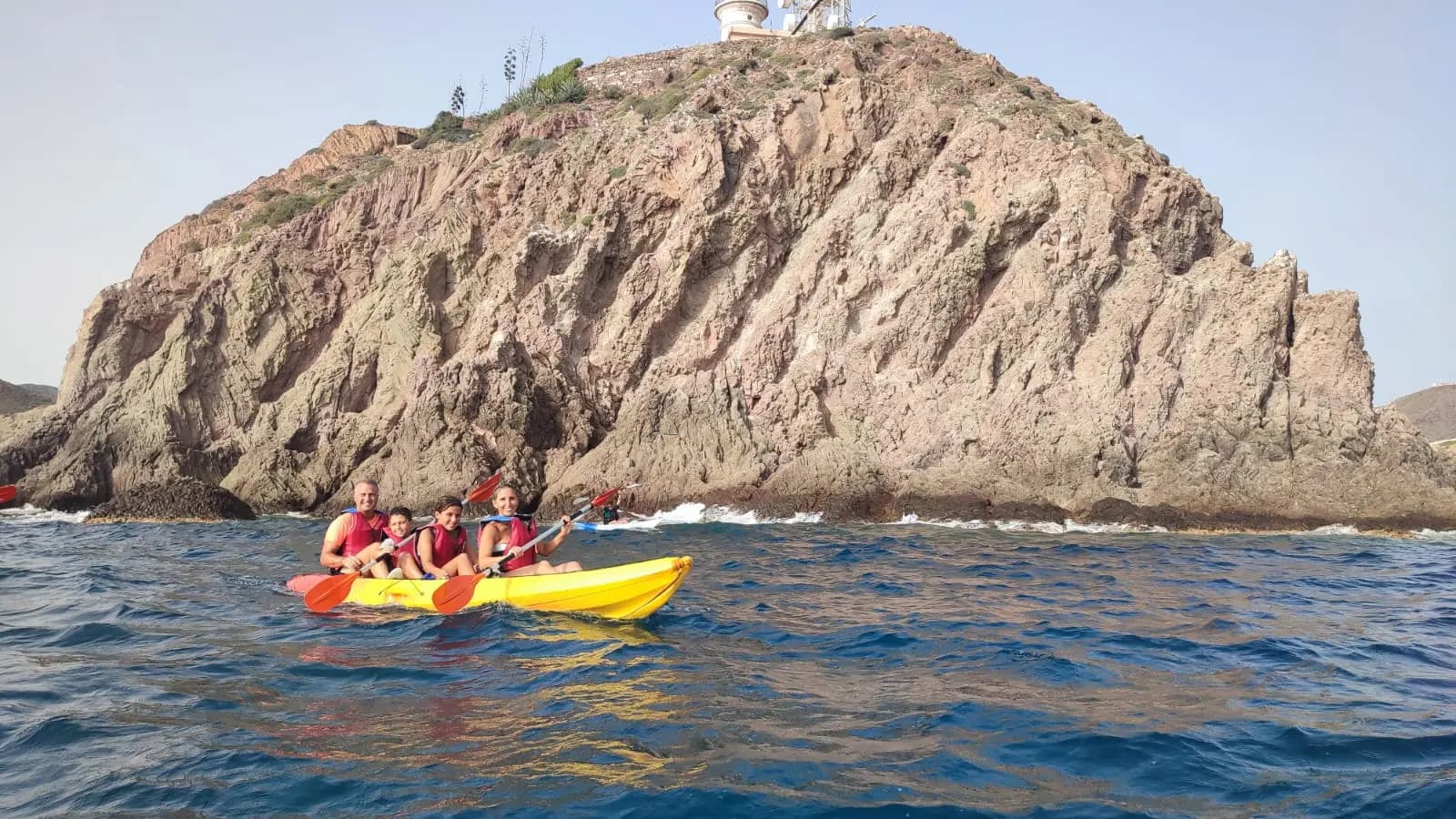 Familia haciendo kayak en aguas tranquilas de Las Negras, Cabo de Gata, padres e hijos con chalecos salvavidas